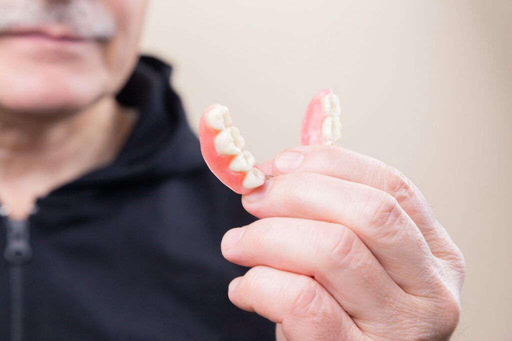 person in black hoodie holding a teeth denture in his hand